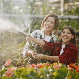 Jeune fille et sa maman arrosant les plantes grâce à la récupération d'eau de pluie Arrosage du jardin grâce à la récupération d'eau de pluie